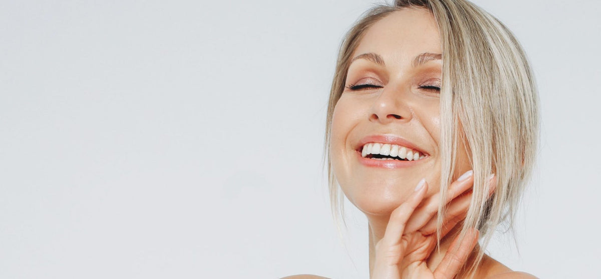 woman smiling with eyes closed and hand facing palm out softly on chin