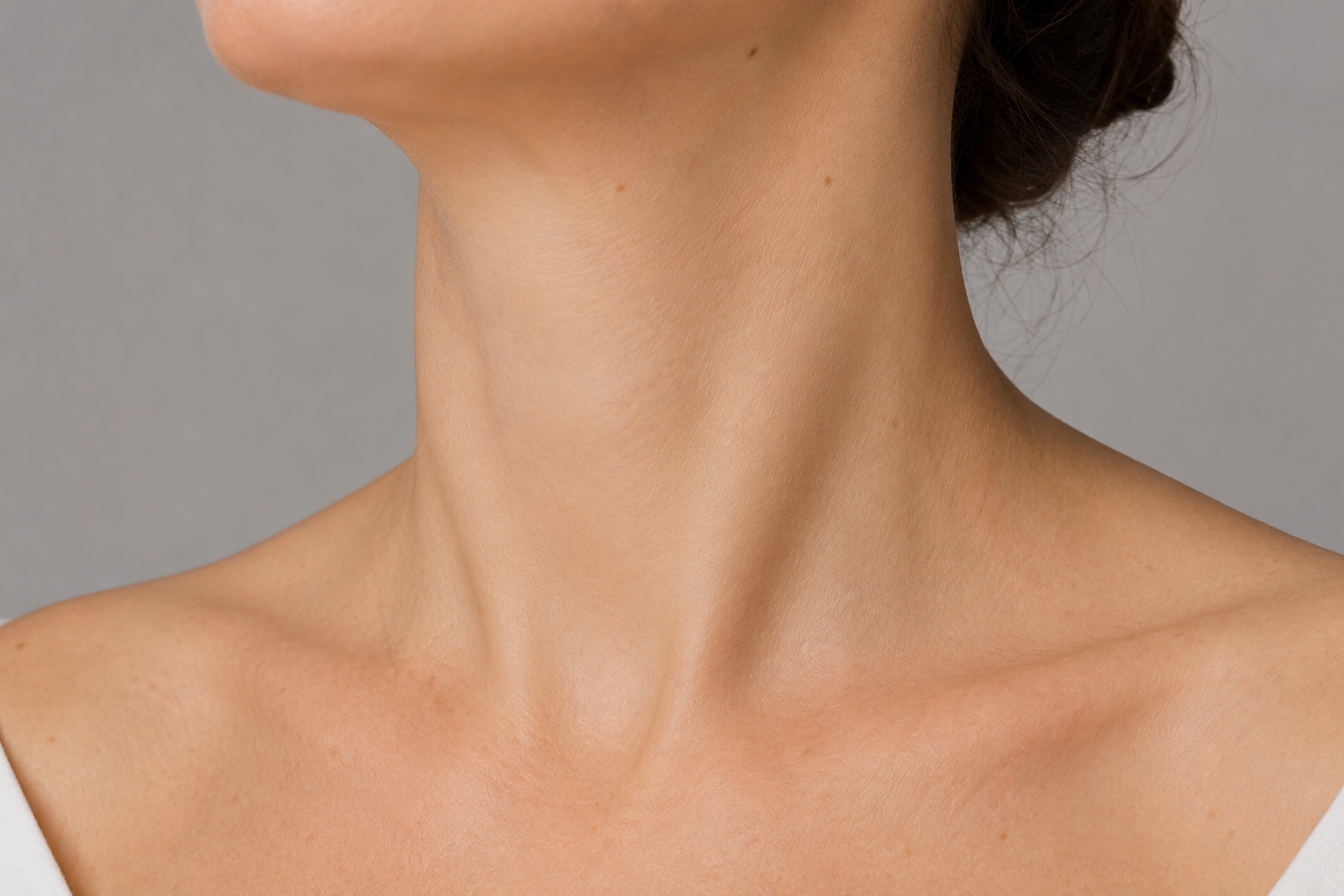 Close-up of a person's neck and shoulders with a neutral background